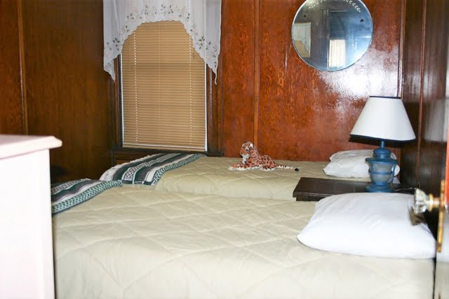 Two beds in a room with wood paneling.