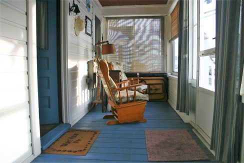 A porch with a rocking chair and blue floor.