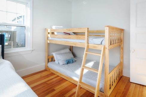 A small bedroom with a bunk bed and a window.