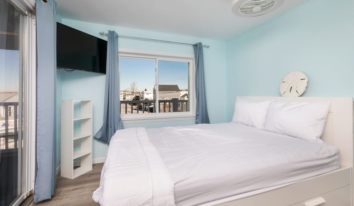 A bedroom with blue walls and a white bed.