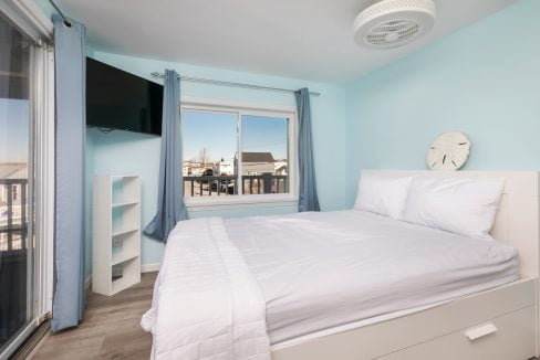 A bedroom with blue walls and a white bed.