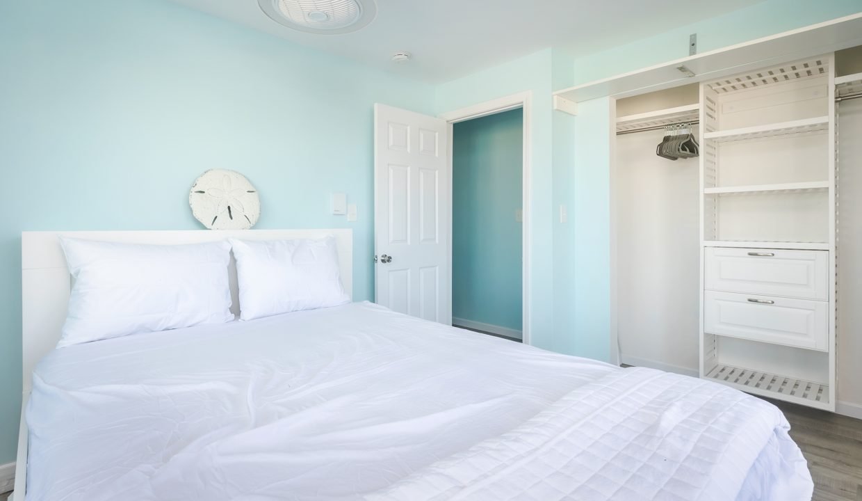 A bedroom with blue walls and a white bed.