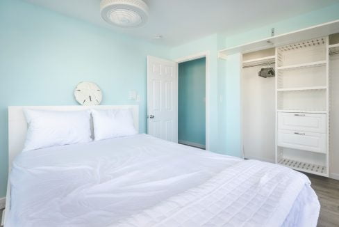 A bedroom with blue walls and a white bed.