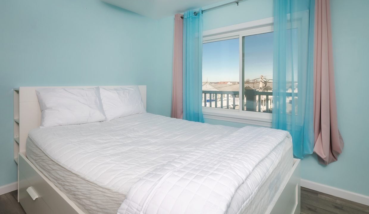 A bedroom with blue walls and a white bed.