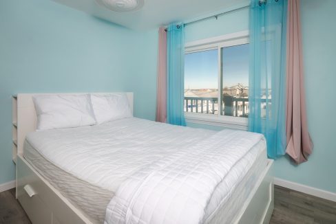 A bedroom with blue walls and a white bed.