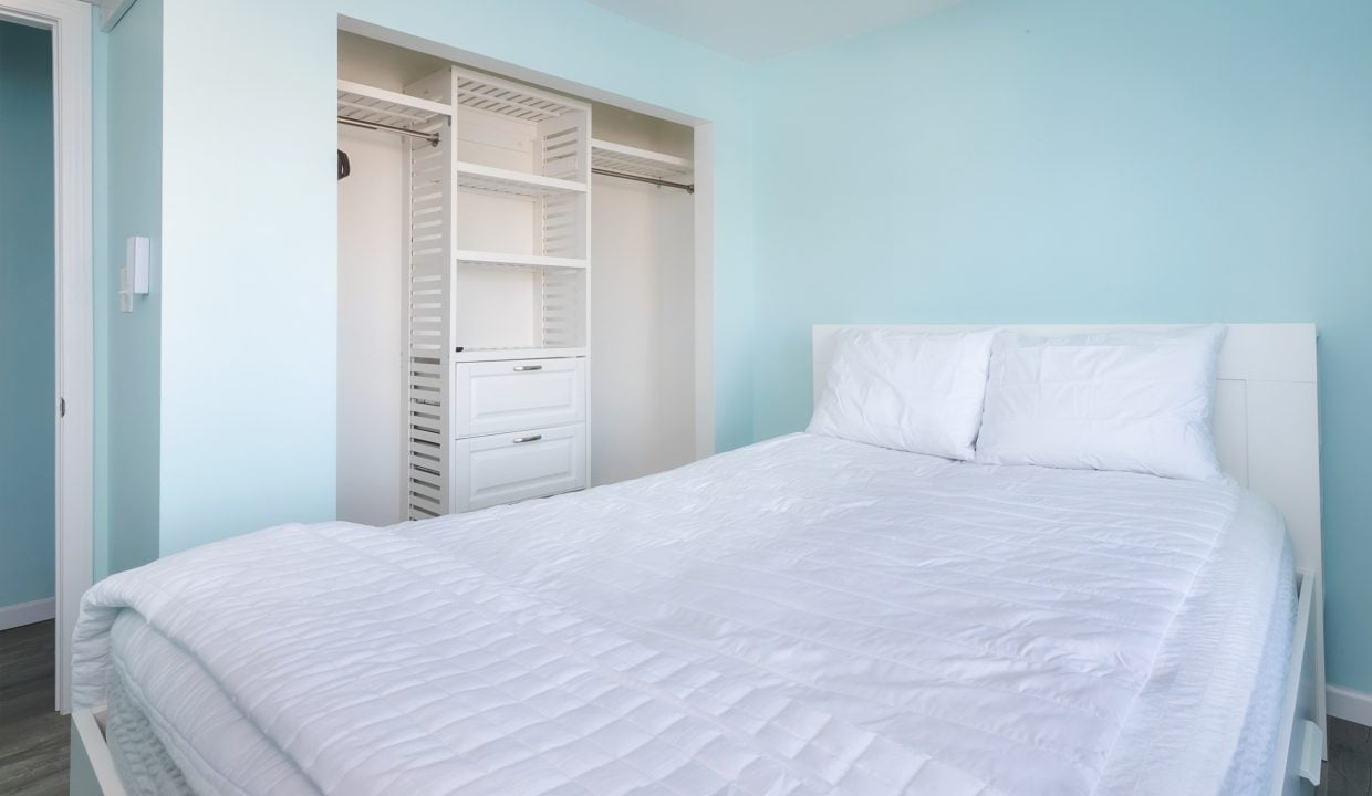 A bedroom with blue walls and a white bed.