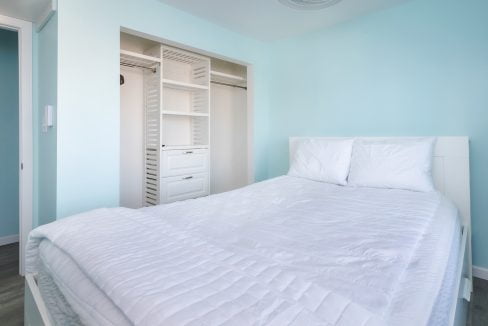 A bedroom with blue walls and a white bed.