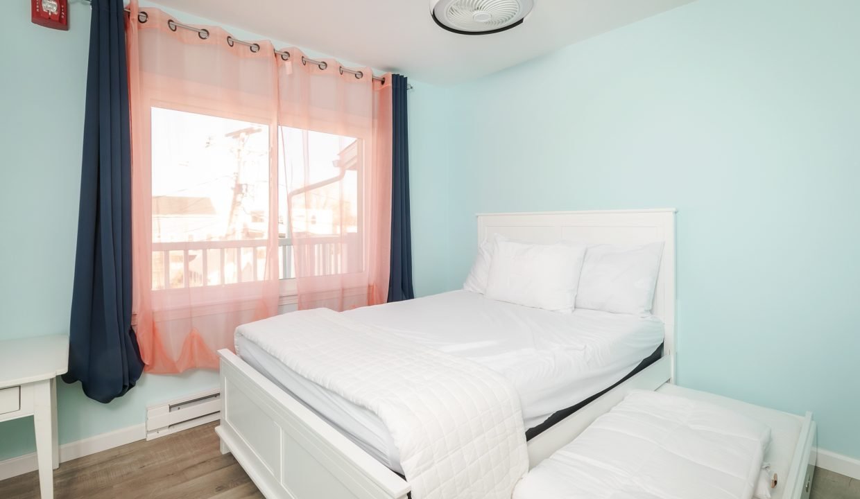 A bedroom with a white bed and blue walls.