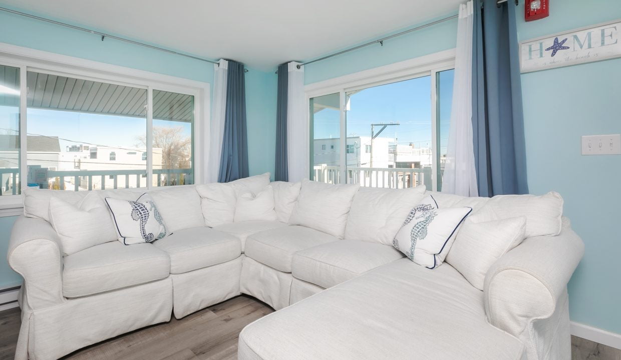 A living room with blue walls and white furniture.