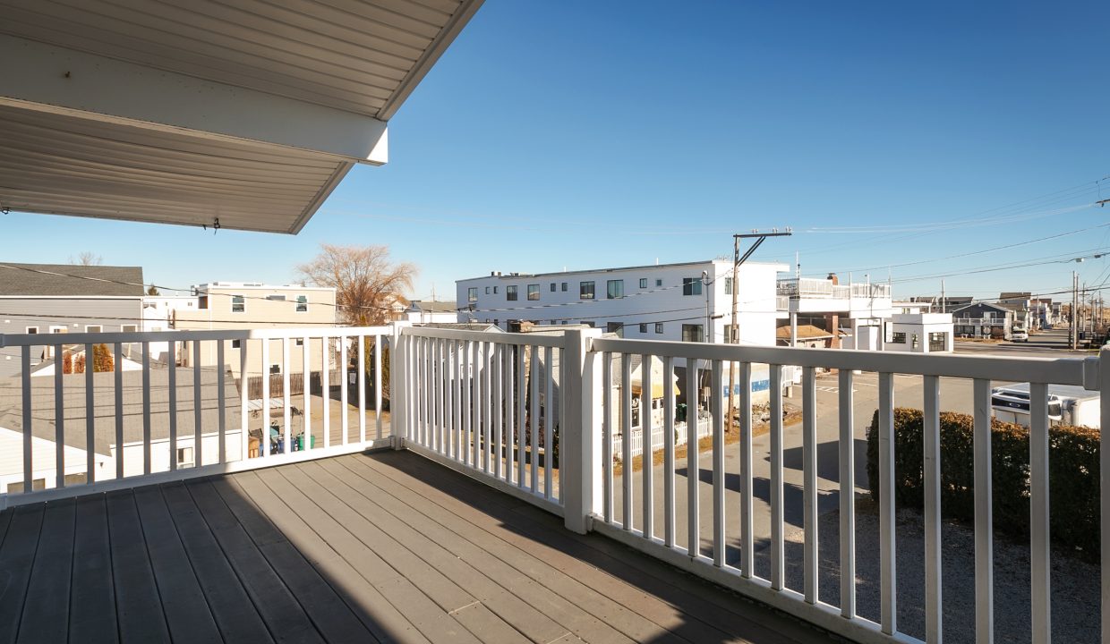 A balcony with a white railing overlooking a street.