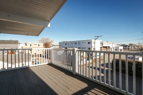 A balcony with a white railing overlooking a street.