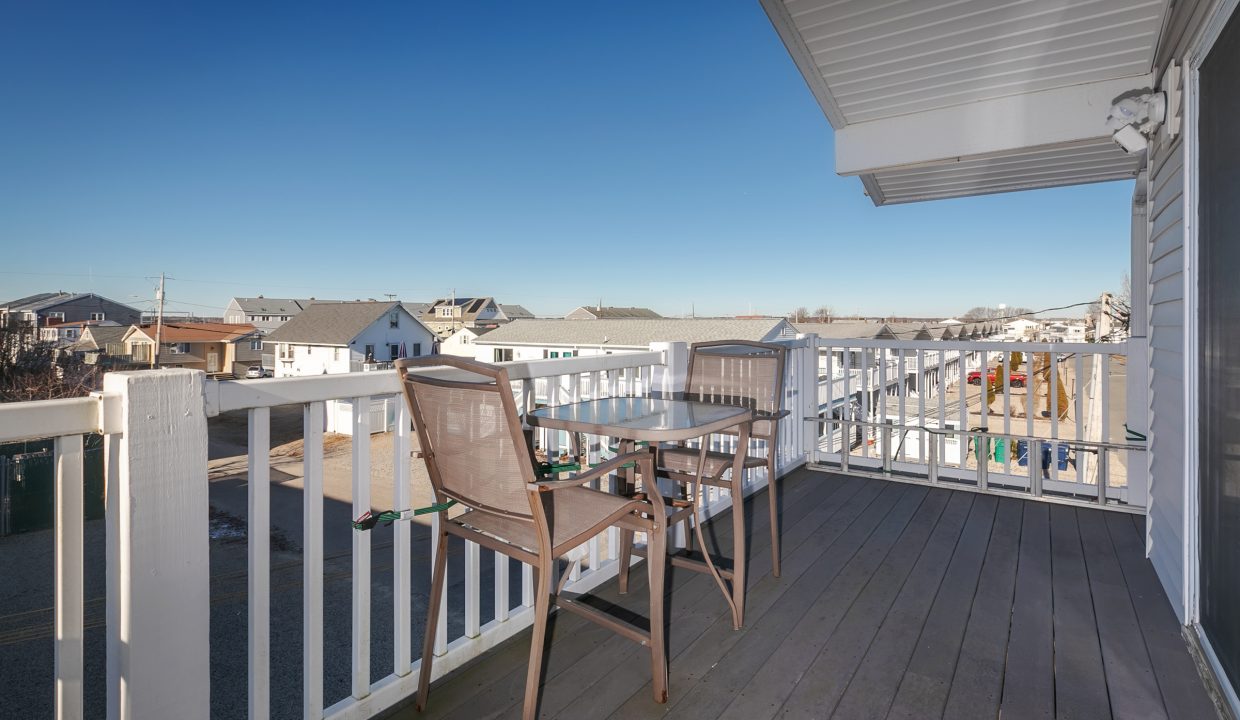 A balcony with a table and chairs overlooking the ocean.