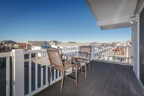 A balcony with a table and chairs overlooking the ocean.