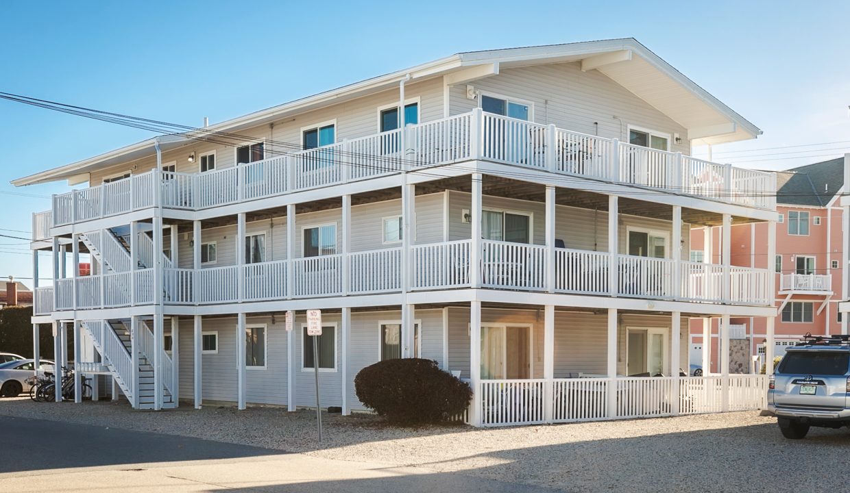 A white apartment building with cars parked in front of it.