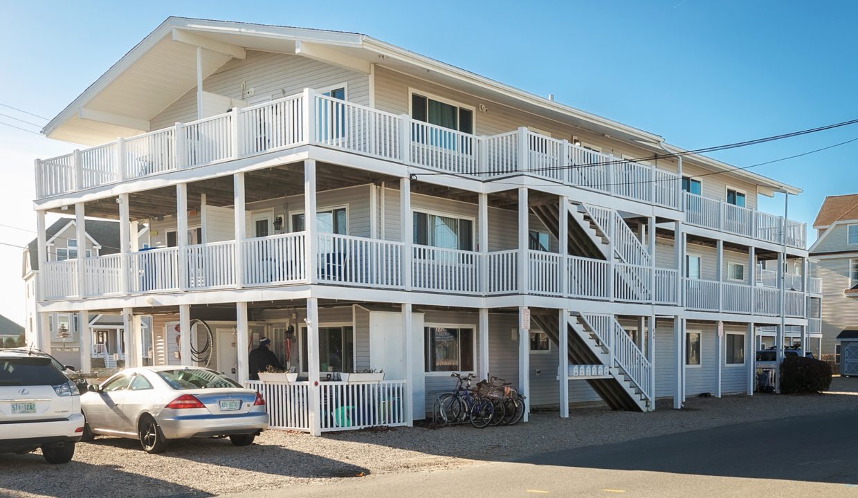 A white apartment building with cars parked in front of it.