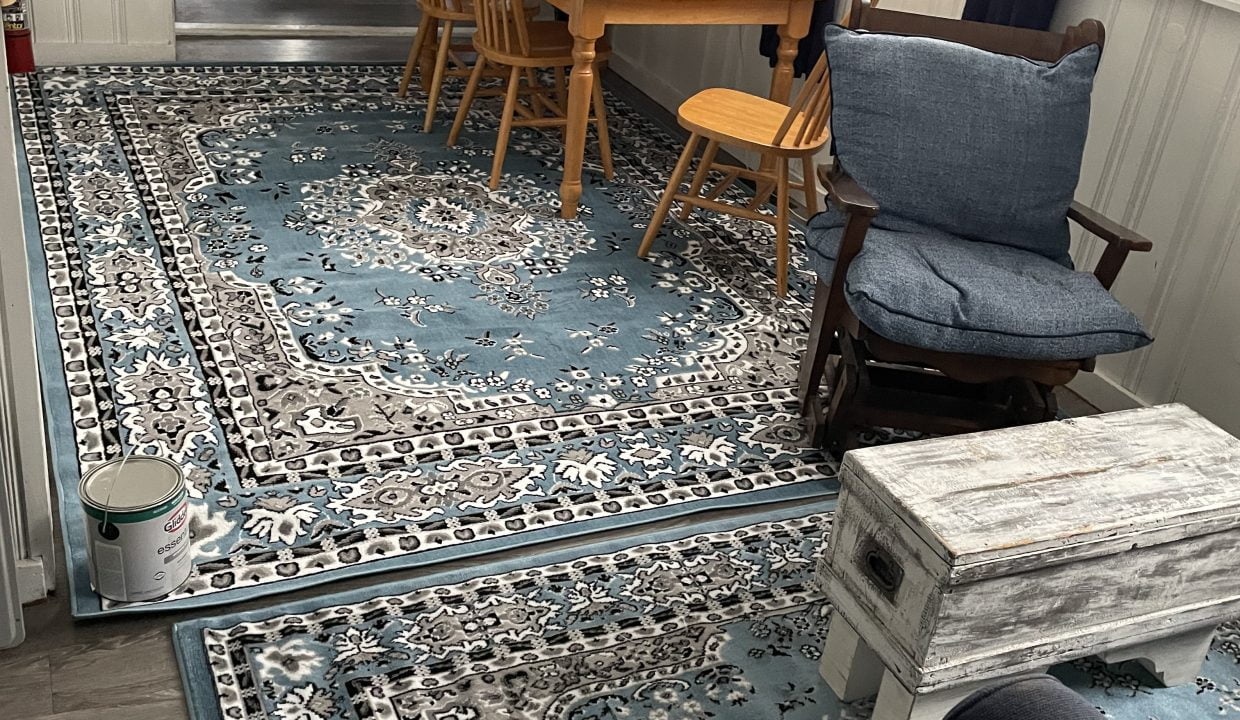 A living room with a blue rug on the floor.