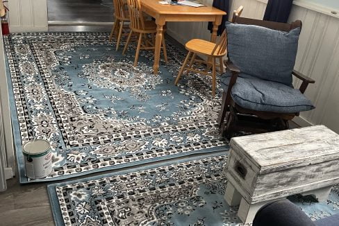 A living room with a blue rug on the floor.