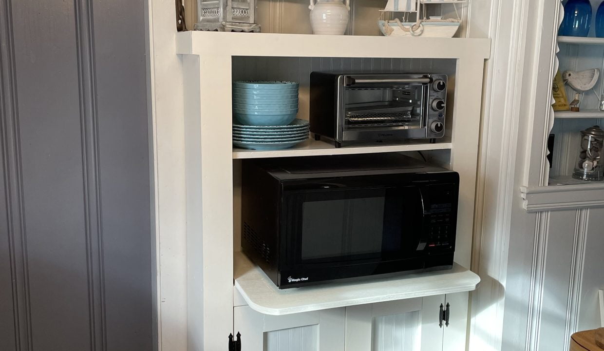 A kitchen with a microwave on top of a cabinet.