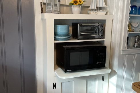 A kitchen with a microwave on top of a cabinet.