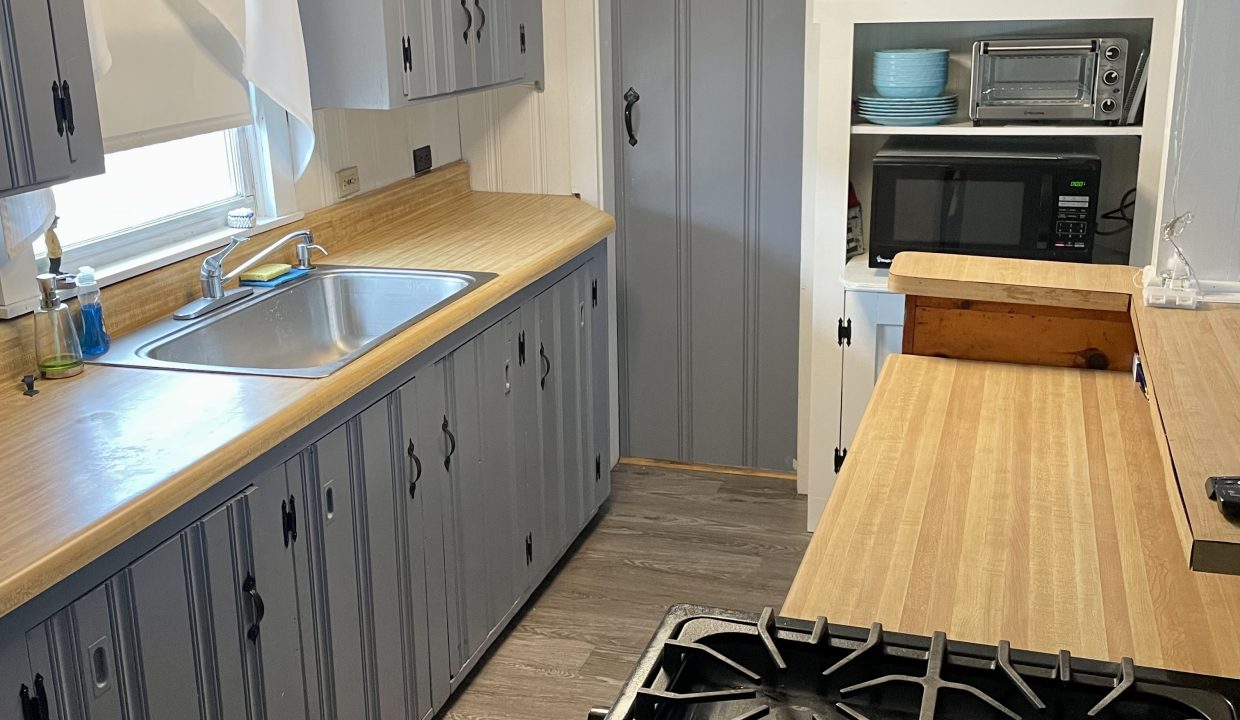 A kitchen with gray cabinets and a stove.