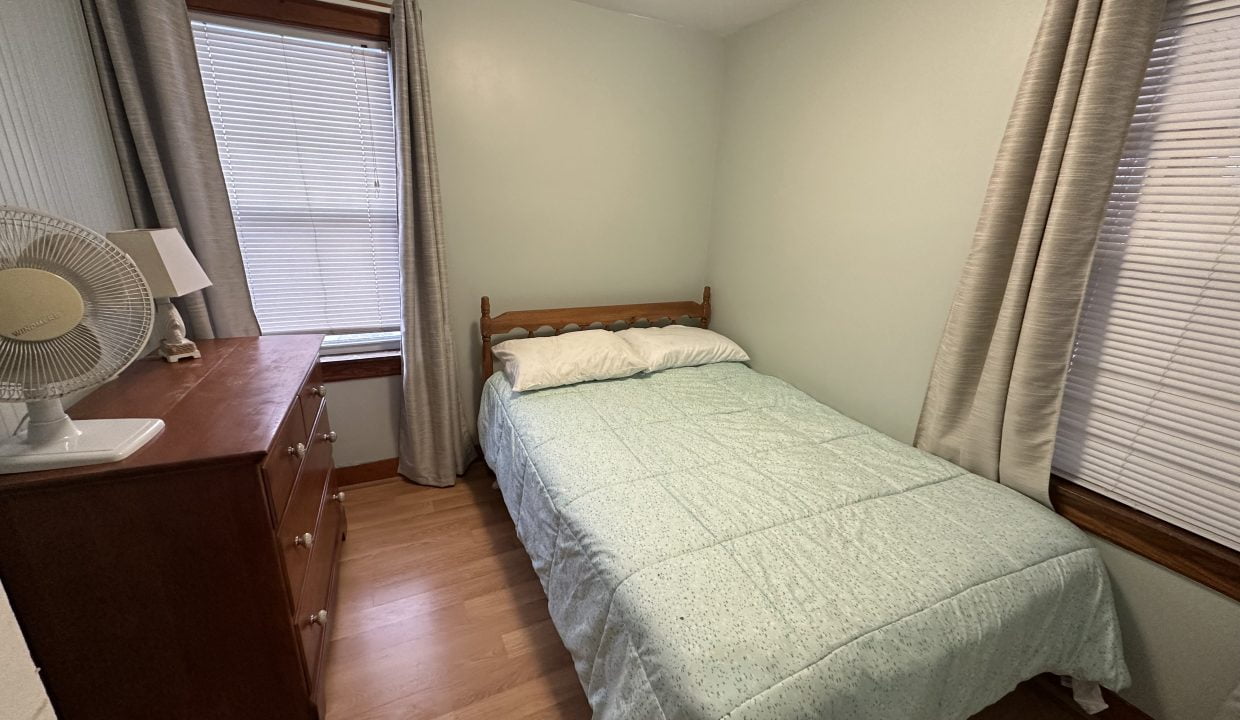 A small bedroom with a bed and dresser.