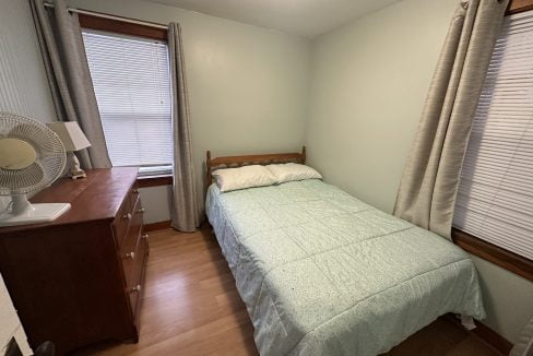 A small bedroom with a bed and dresser.