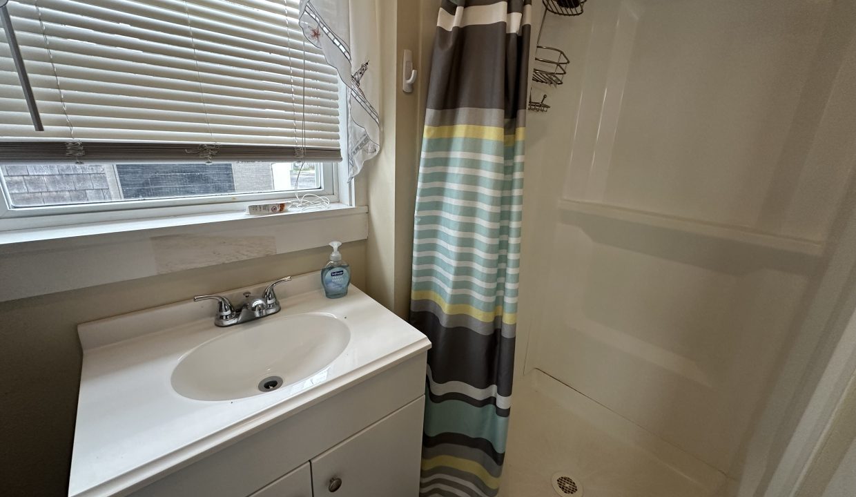 A small bathroom with a shower and sink.