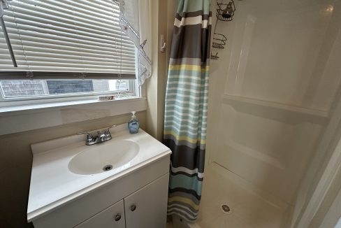A small bathroom with a shower and sink.