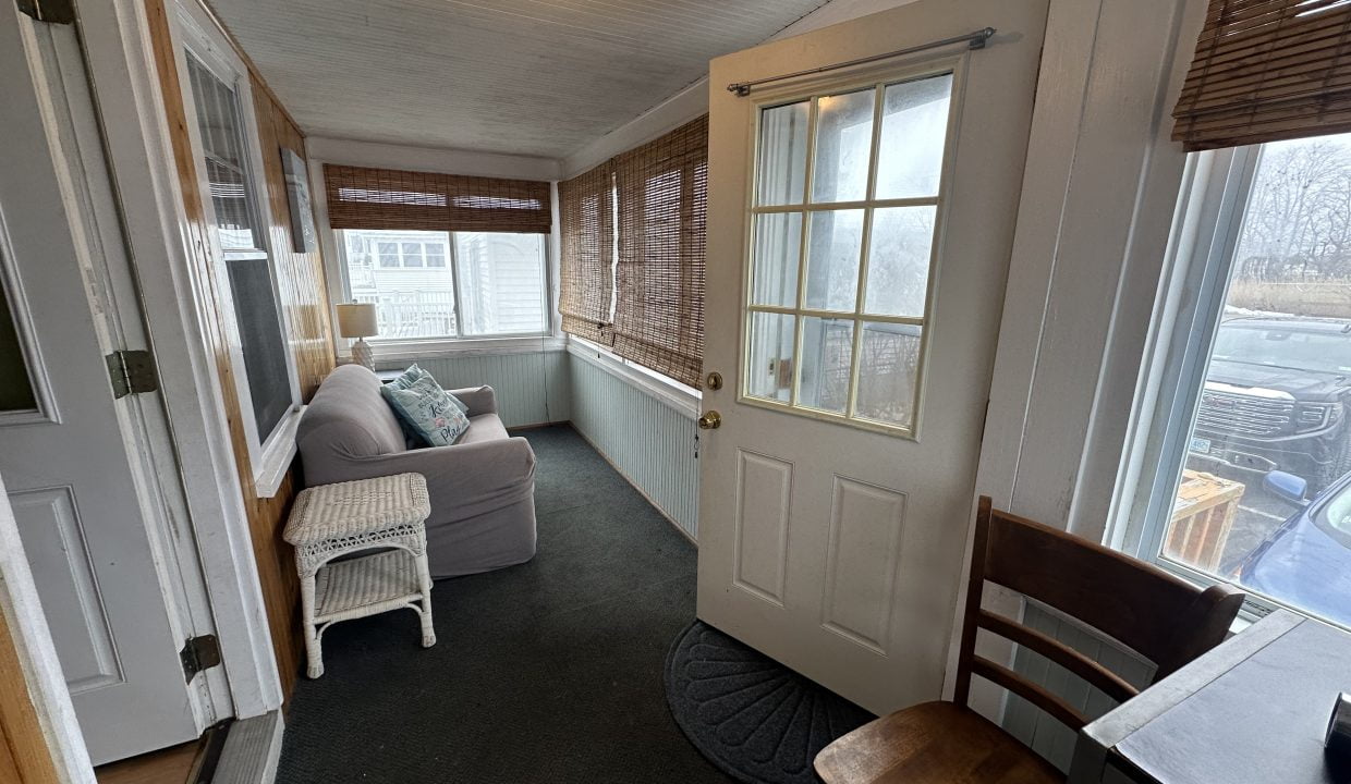 A living room with a couch and a door leading to a porch.