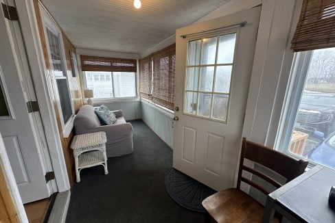 A living room with a couch and a door leading to a porch.