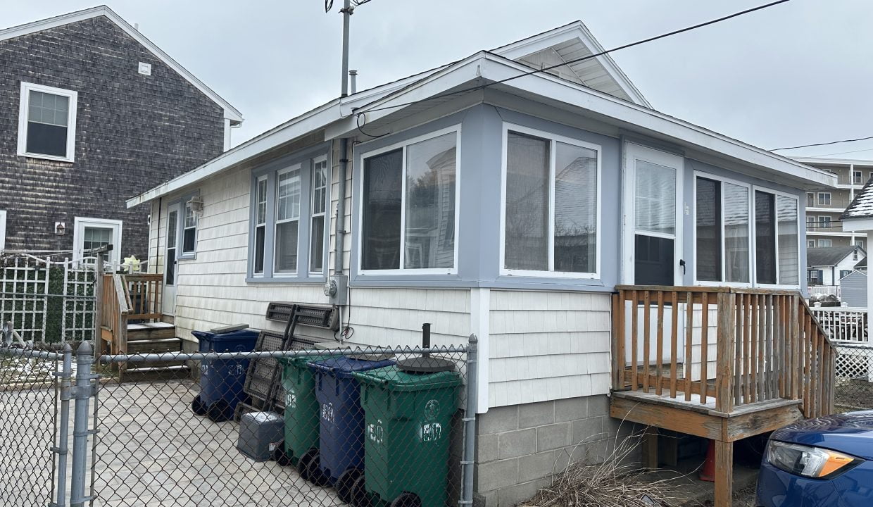 A house with a garbage can in front of it.