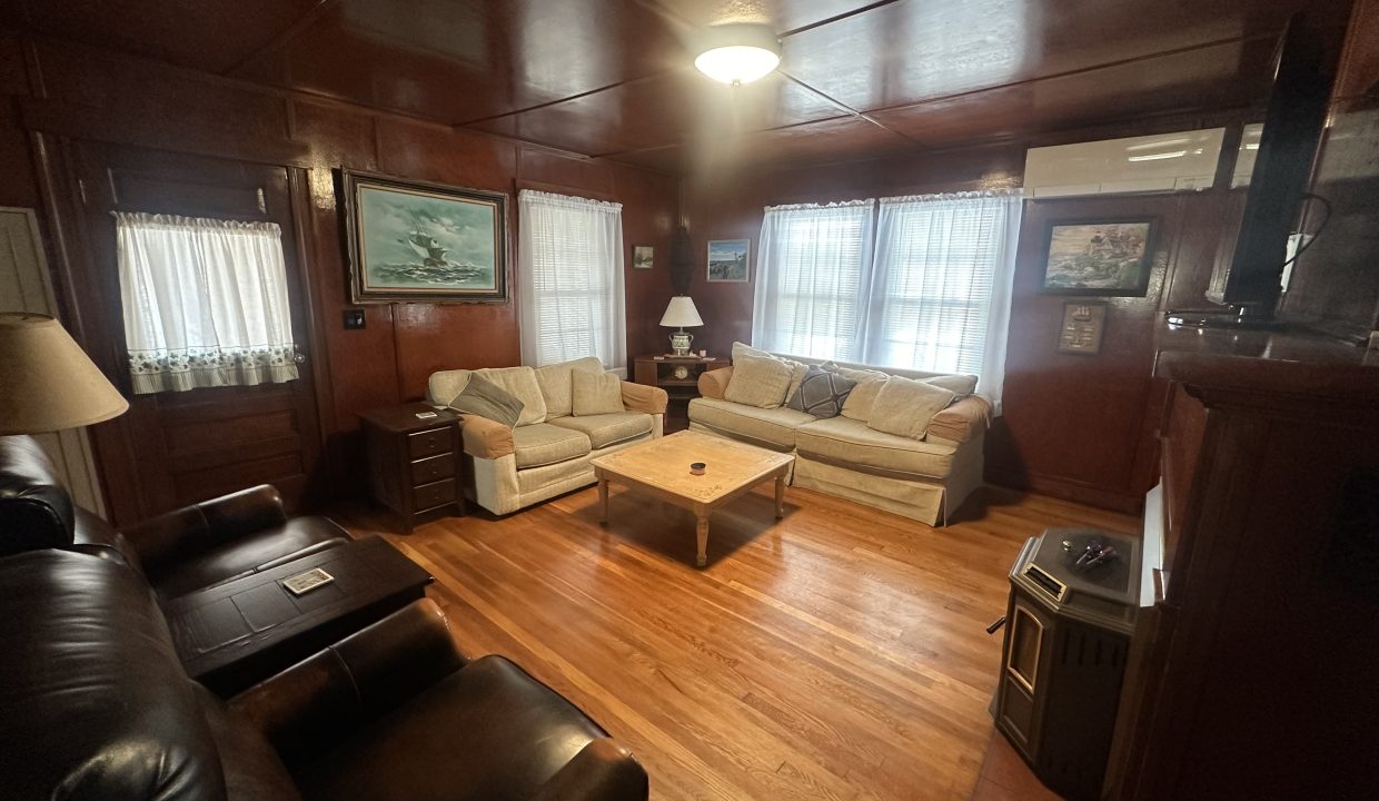 A cozy, traditional living room with wooden walls, hardwood flooring, and classic furniture.