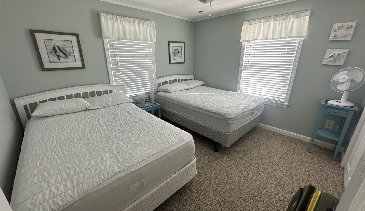 A tidy bedroom with two single beds, light blue walls, and matching decor.