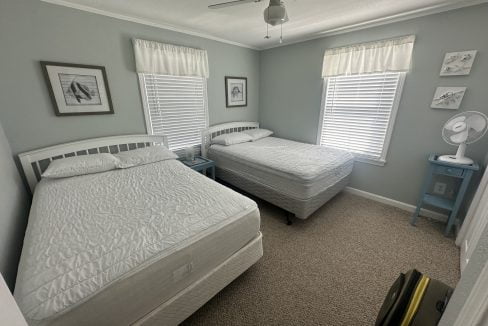 A tidy bedroom with two single beds, light blue walls, and matching decor.