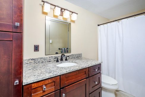 A bathroom with a marble countertop and a toilet.