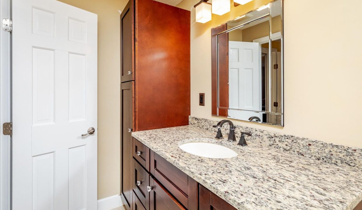 A bathroom with granite counter tops and a mirror.