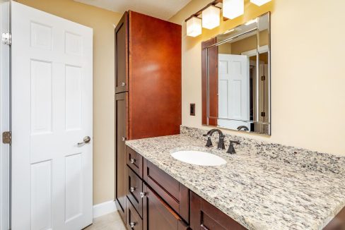 A bathroom with granite counter tops and a mirror.