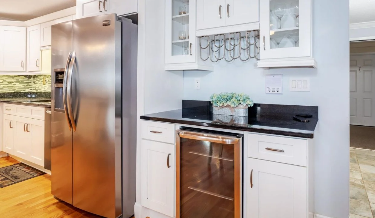 A kitchen with a stainless steel refrigerator and white cabinets.