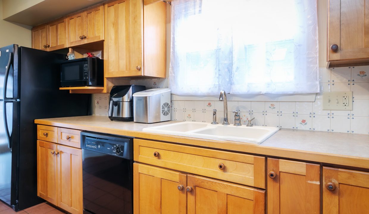 A kitchen with wooden cabinets and a black microwave.