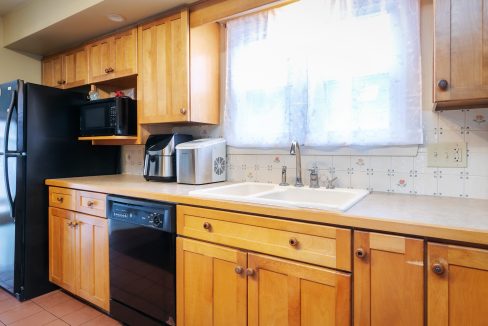 A kitchen with wooden cabinets and a black microwave.