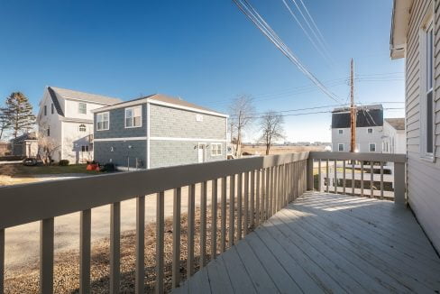 A deck with a railing and a view of a house.