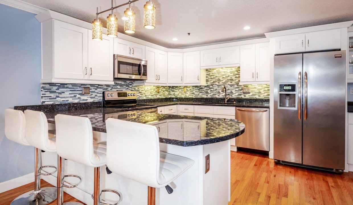 A kitchen with white cabinets and black granite counter tops.