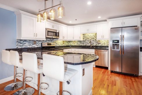 A kitchen with white cabinets and black granite counter tops.