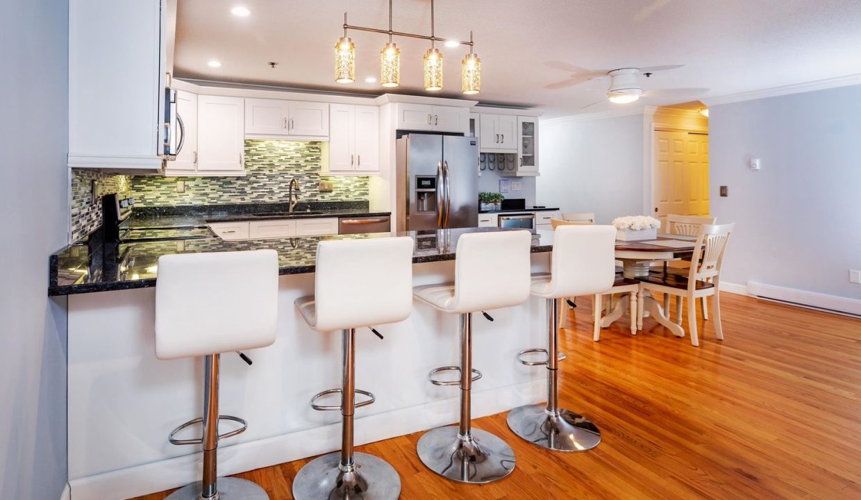 A kitchen with white cabinets and white chairs.