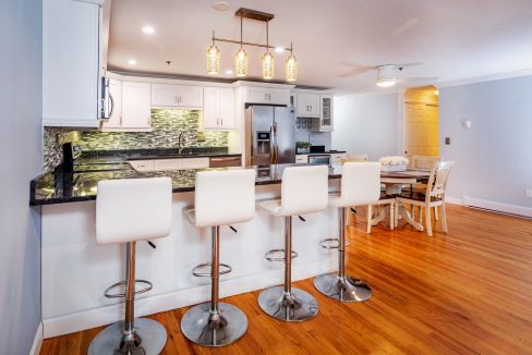 A kitchen with white cabinets and white chairs.