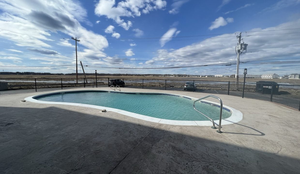 A pool in a parking lot with a cloudy sky.