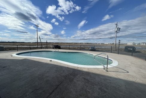 A pool in a parking lot with a cloudy sky.