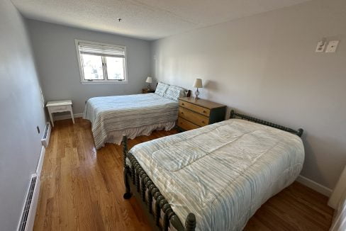 Two beds in a room with hardwood floors.