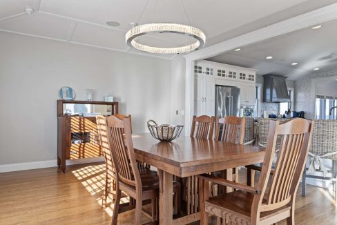 A spacious dining room featuring a large wooden table with chairs and an elegant chandelier.