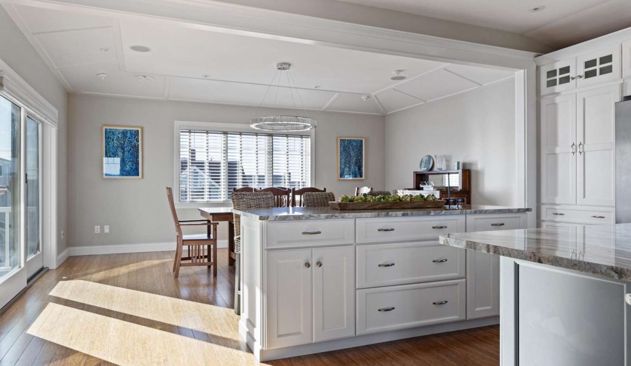 A bright, modern kitchen with white cabinetry, stainless steel appliances, hardwood floors, and a central island.